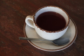 A warm, cozy cup of soothing herbal tea with a delectable chocolate rim on a lovely wooden table