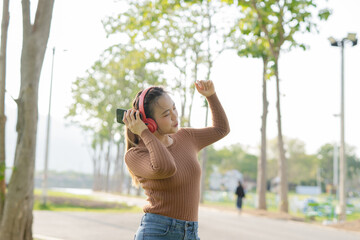 Asian woman using headphones to dance
Outdoors, park