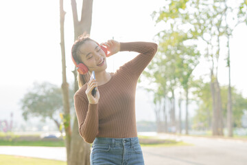 Asian woman using headphones to dance
Outdoors, park