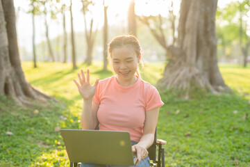 Asian woman sitting working under a tree outdoors in the evening light.