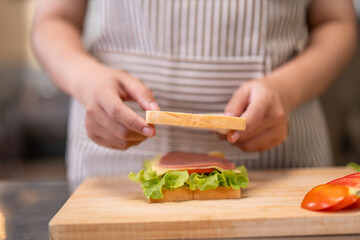 Smiling Young Female Chef Preparing a Sandwich in a Professional Kitchen