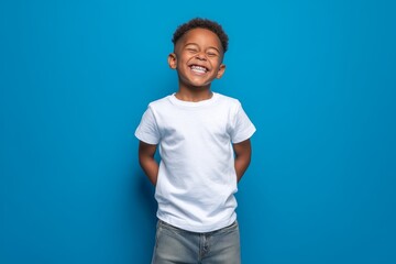 Happy smilling boy wearing bella canvas white shirt mockup, at blue background. Design tshirt template, print presentation mock-up