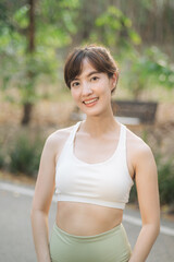 Fototapeta premium Asian woman outdoor workout. Healthy and active lifestyle concept. Smiling young woman in sportswear enjoying exercise in natural park