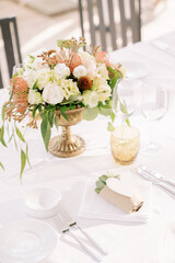 Bouquet of flowers stands on a festive table next to an invitation succulent in a paper cup with a heart