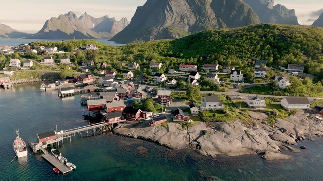 Explore a picturesque coastal village in Reine Lofoten Norway surrounded by towering mountains and serene waters. The charming houses and vibrant harbor create a tranquil atmosphere.