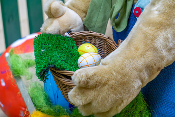 Easter decoration depicting a figurine of a bunny holding a basket. The basket contains colorful...
