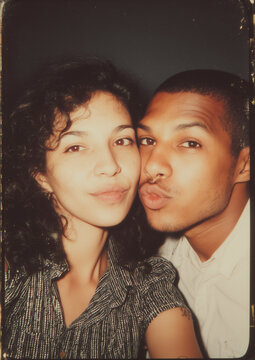 vintage photo booth film of mixed race couple pulling silly faces in 80s - 90s in color