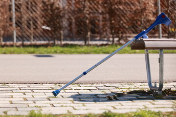 A blue cane is leaning against a bench