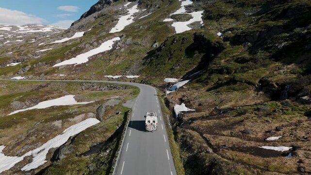 Stunning journey along a winding road in Norway, surrounded by majestic mountains and patches of snow. camper van on the Norwegian County Road 63, Geiranger Trollstigen Langvatnet route, Norway