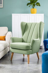 sage green wingback chair with vertical channel tufting sits in a contemporary living room setting