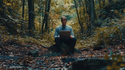 Fototapeta premium Focused man working on laptop in a serene forest setting.