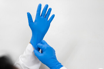 Woman doctor putting blue latex medical gloves on white background.Surgeon wearing gloves before surgery at operating room.Risk and infection control concept