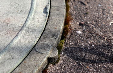 Fragment of stone well cover, grainy texture of stone, concrete with red-green moss on surface in sunlight - horizontal color macro photo, top view