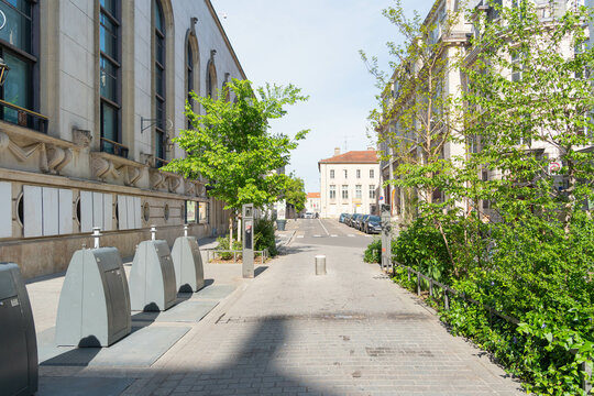 Rue Pierre Fourrier in Nancy, France, a peaceful street near the city hall, with trees, bicycles, and light-colored historic buildings bathed in spring sunlight.