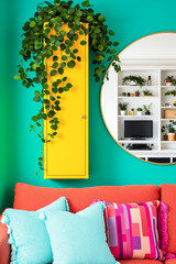 yellow cabinet with trailing plants on a teal wall in a modern living room