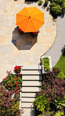 orange umbrella on a modern stone patio surrounded by lush greenery
