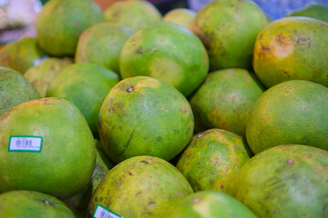 Close-up of Fresh Green Citrus Fruits with Price Tags at Market Stall
