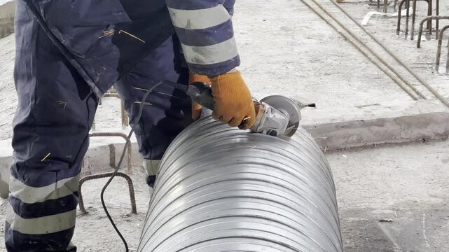 The worker cuts the pipe at the construction site with a grinder