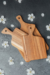 Wooden cutting boards arranged on a dark surface with flowers