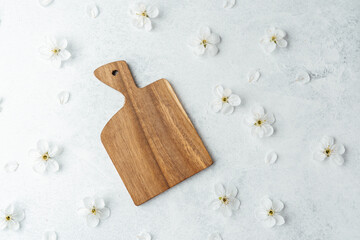 Wooden serving board on a textured surface with delicate white flowers