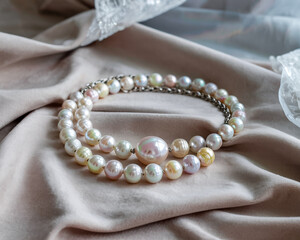 Elegant Pearl Necklace Featuring Pastel Colors On A Soft Beige Fabric