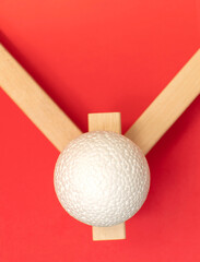 Still life with wooden blocks and a a plastic foam ball on red background