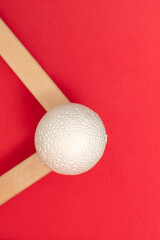 Still life with wooden blocks and a a plastic foam ball on red background
