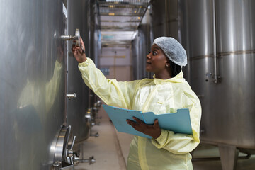 Wine factory, wine production, produces wine. Winemaker inspecting quality the process of fermentation during manufacturing in winery factory and stainless tank