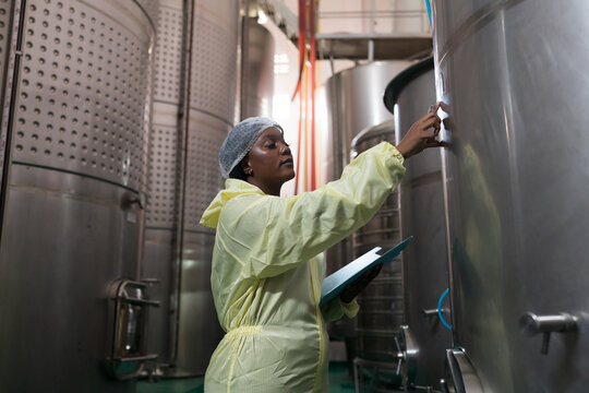Wine factory, wine production, produces wine. Winemaker inspecting quality the process of fermentation during manufacturing in winery factory and stainless tank