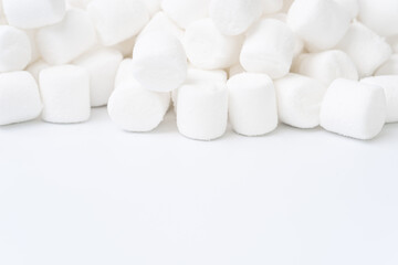 Heap of mini white marshmallows on a white background, perfect for dessert recipes, holiday treats, and baking-themed visuals.