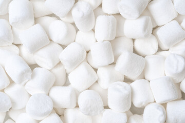 Close-up of mini white marshmallows scattered randomly. Ideal for dessert, baking, sweet treats, and festive backgrounds.