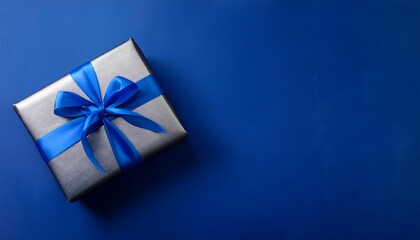 Gray Gift Box with Blue Ribbon on Dark Blue Background. Top View of Brotherhood Day Gifts with Copy Space