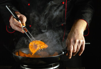 A chef maneuvers tongs to expertly flip golden pumpkin slices sizzling in a frying pan. Wisps of...