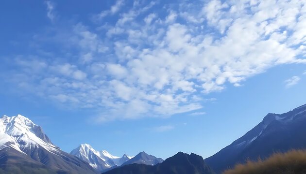 Majestic snow-capped mountains under a vibrant blue sky with fluffy clouds