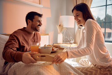 Happy woman surprising her boyfriend with breakfast in bed.