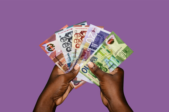 Black african hands holding various Ghanaian cedi notes over purple background. closeup of Hands holding Ghana paper currencies. 