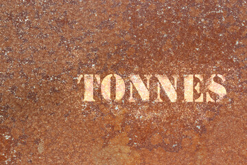 Tonnes sprayed in white with stencil on old aged rusty metal background backdrop.