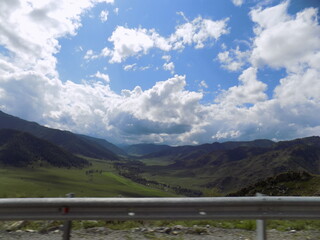 Rolling hills and dramatic clouds over a lush valley with distant mountains in a serene landscape