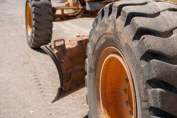 A close-up view of a large, rugged tire with deep treads, showcasing an orange rim. The background...