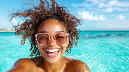 A bright and cheerful woman with curly hair smiles widely while enjoying a sun-soaked day at the beach, capturing a moment of joy and freedom in the sparkling turquoise waters.
