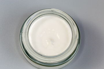 Open small glass jar of cosmetic cream, top view