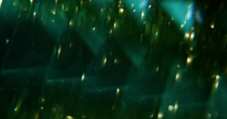Glowing lights. Defocused shimmering radiance. Bright green sparkling color flare on blurred dark black abstract modern background with bokeh effect. © golubovy