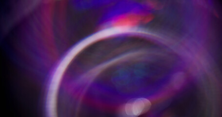 Multicolor flashes. Defocused gleaming circling. Purple neon color sparkling particles motion on dark black blurred abstract bokeh light background.
