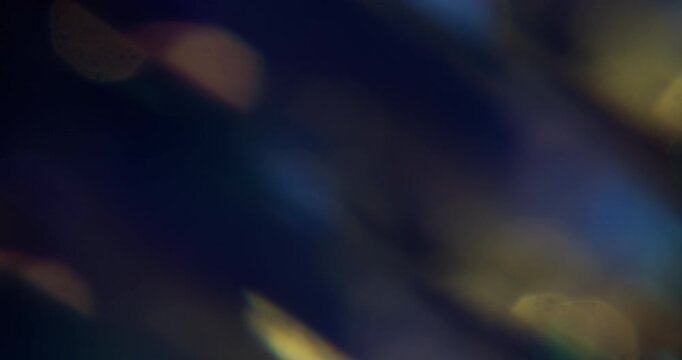 Glint lens. Blur spark texture. Defocused yellow blue purple multicolor magical light flicker on abstract art dark black background.