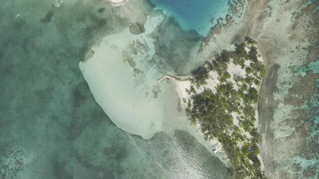 Drone rockets upward with camera pointing down at Water Cay on a cloudy day in Utila, Honduras