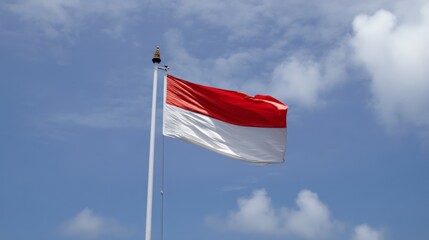 Indonesian flag waving against blue sky with clouds