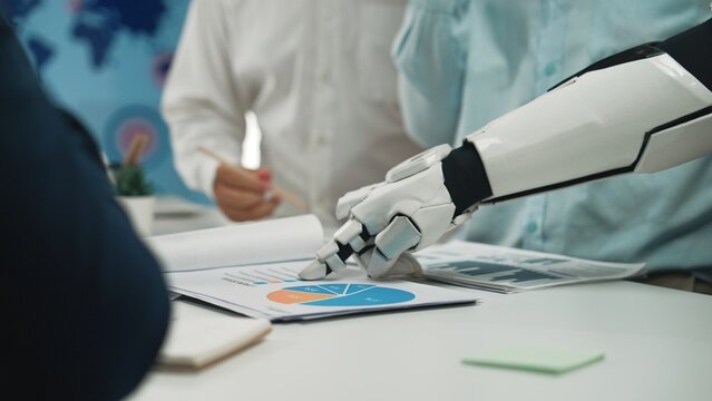 A robotic arm points at colorful charts and graphs, highlighting the fusion of technology and human tasks for improved decision making in modern business environments.Noogenesis