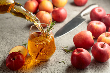 Apple cider is poured from a bottle into a glass.