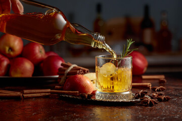 Apple cider is poured from a bottle into a crystal glass.
