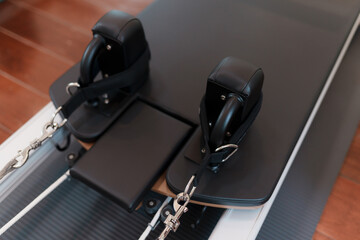Close-up of Pilates reformer machine in modern fitness studio. Equipment used for body alignment,...